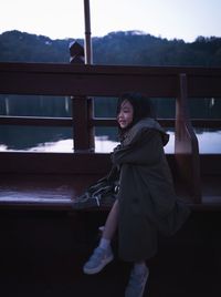 Smiling young woman standing by railing against mountain