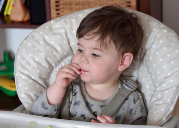 Portrait of baby boy eating cucumbers in the high chair