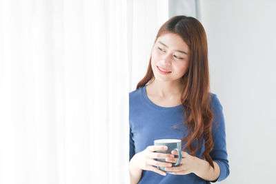 Portrait of smiling young woman holding smart phone