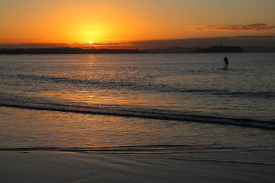 Silhouette people on beach against sky during sunset