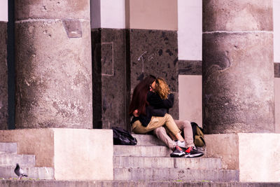 Full length of woman sitting on staircase in city