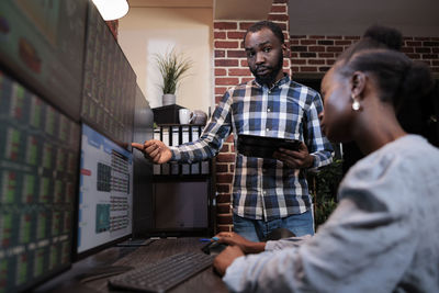 Side view of young man using digital tablet while standing in office