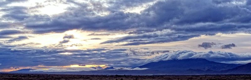 Scenic view of sea and mountains against dramatic sky