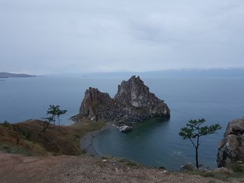 Scenic view of rocks on sea shore against sky