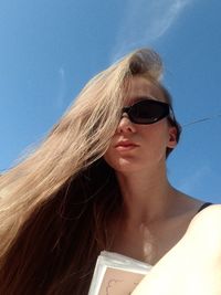 Portrait of young woman in sunglasses against sky