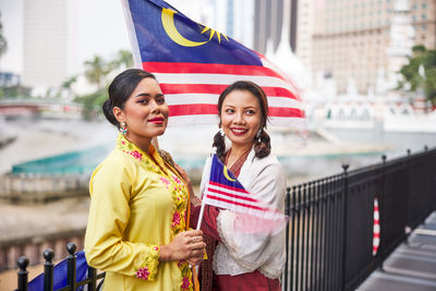 Portrait of smiling woman holding map while standing in city