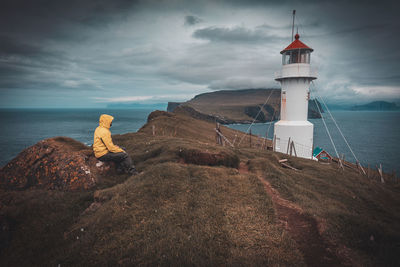 Man sitting on mountain by sea