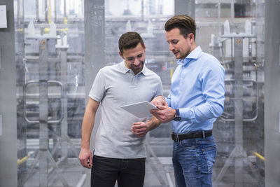 Two men with tablet talking in factory shop floor