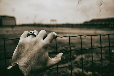 Close-up of man hand on metallic fence