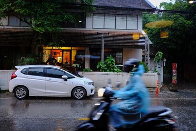 Man riding car on street against buildings in city