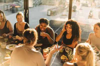 Multiracial female friends talking to each other while having breakfast at retreat center