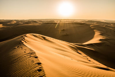 Scenic view of desert against clear sky during sunset