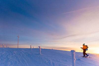 Woman skiing on snow covered mountain against sky