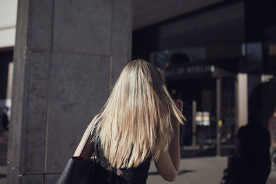 Portrait of beautiful young woman standing against buildings in city