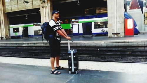 Side view of man standing at railroad station