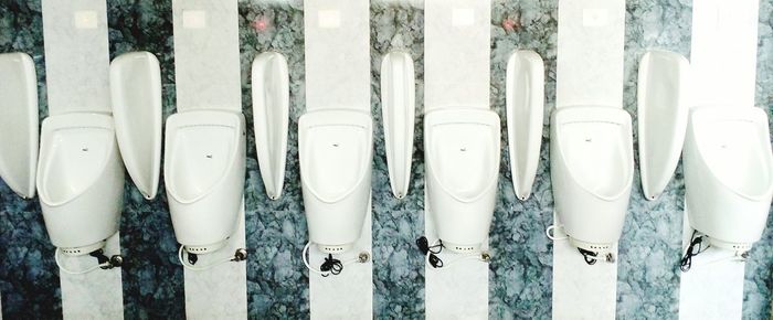 Panoramic view of white ceramic urinals on wall at public restroom