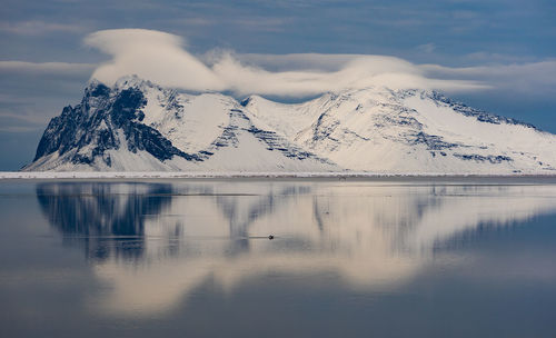 Scenic view of lake by snowcapped mountains against sky