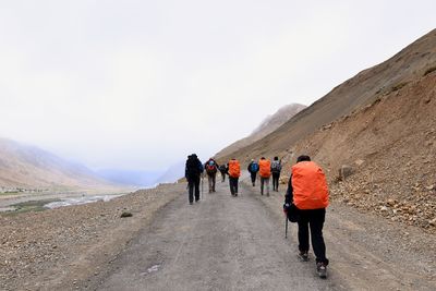 Rear view of people walking on road against mountain