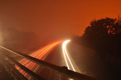 Light trails on road against sky at night