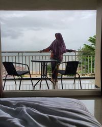 Rear view of woman sitting on bed at home