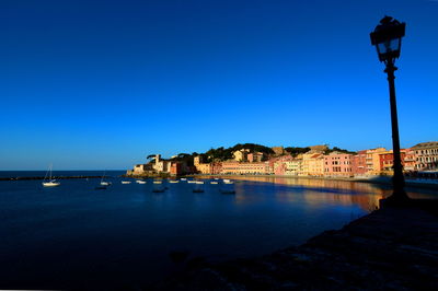 Built structure by sea against clear blue sky