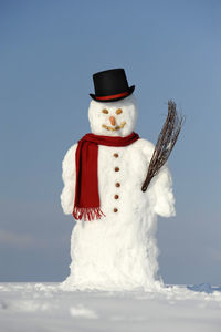 Snowman on field against blue sky