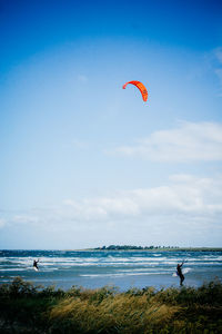 Men kiteboarding on sea against sky