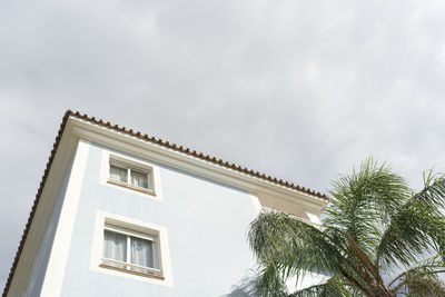 Low angle view of palm tree and building against sky