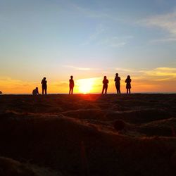 Silhouette people standing on land against sky during sunset