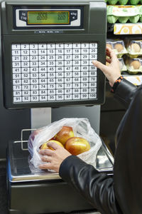 Midsection of person weighing apples on scale