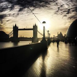 View of suspension bridge in city at sunset