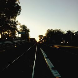 Railway tracks and trees against clear sky