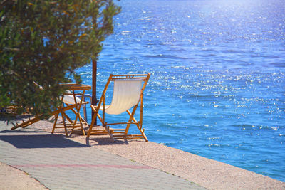 Chair on footpath by sea