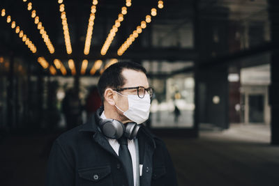 Businessman with headphones looking away during pandemic