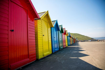 Multi colored huts on road amidst buildings against blue sky