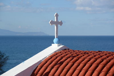 Cross on sea against sky