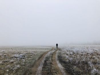 Silhouette of a man in the middle of a field covered in snow