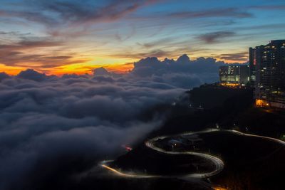 Aerial view of illuminated city buildings against dramatic sky