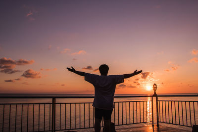 Silhouette man standing by sea against sky during sunset