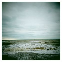 Scenic view of beach against cloudy sky