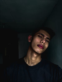 Portrait of young man standing against black background