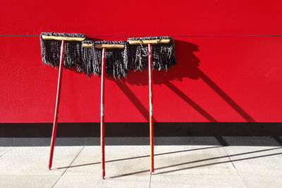 Brooms on red wall