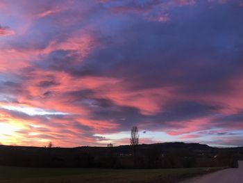 Silhouette landscape against dramatic sky during sunset