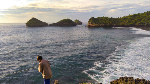 Rear view of man looking at sea against sky