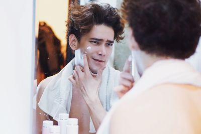 Young man shaving in bathroom