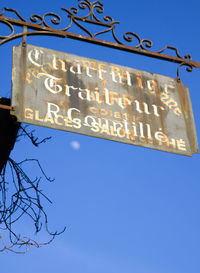 Low angle view of road sign against blue sky