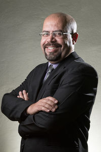 Portrait of mature bald businessman smiling while standing against gray wall