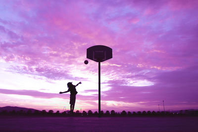 Silhouette man playing basketball against sky during sunset