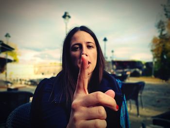 Close-up portrait of woman pointing against sky