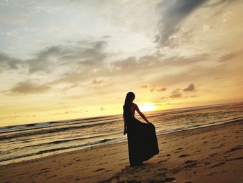 Silhouette person on beach against sky during sunset